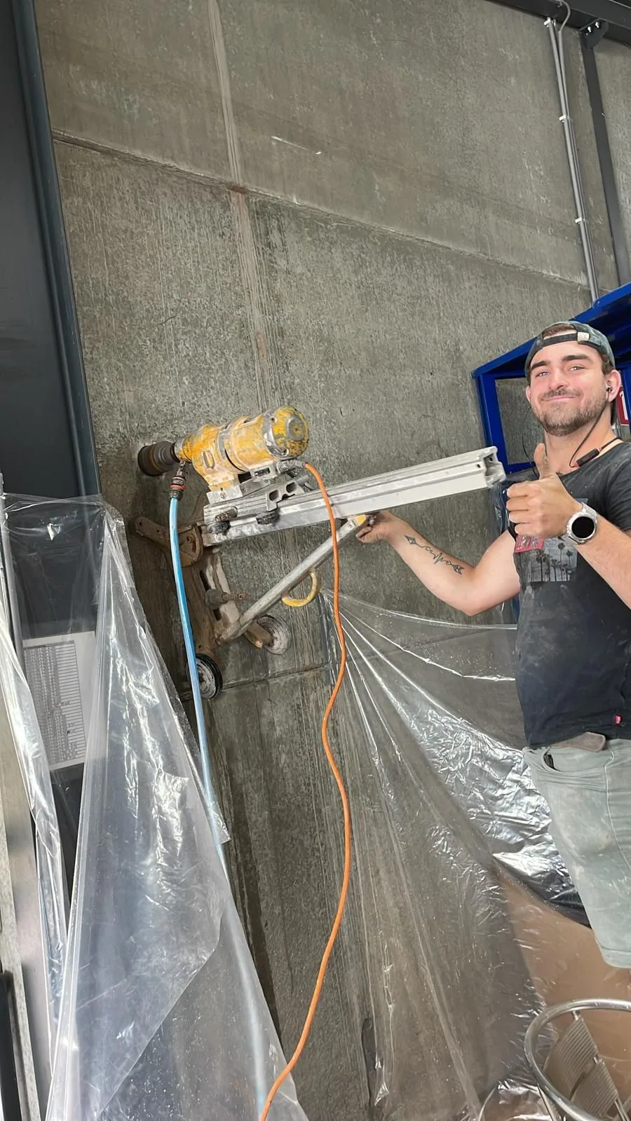 Medewerker naast een horizontale diamantboor op statief tegen een wand